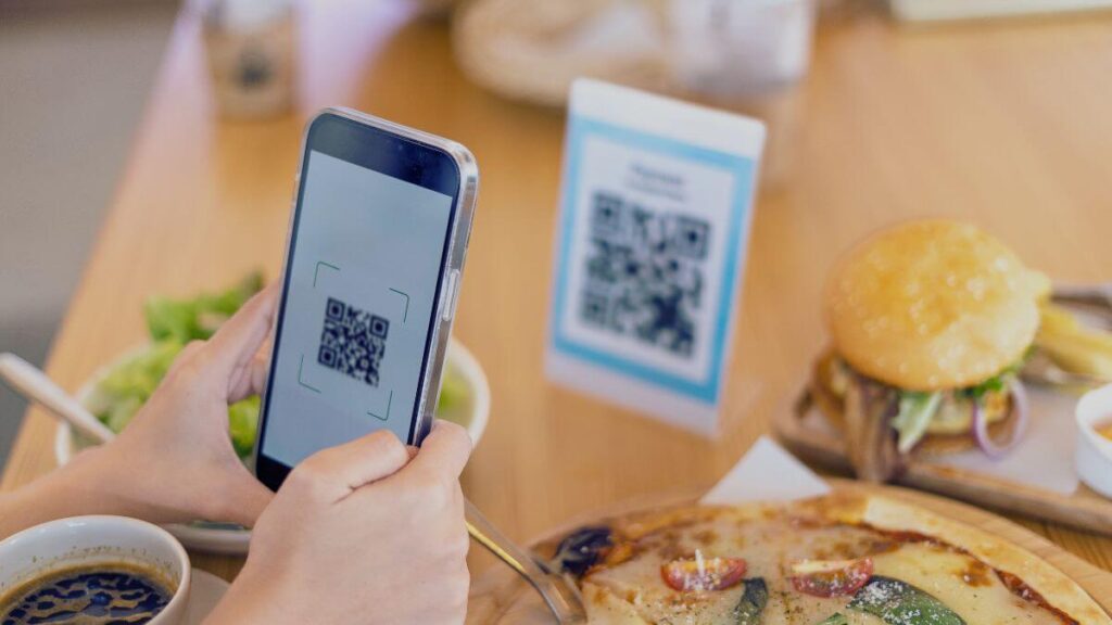 customer scanning a QR code sign on a dining table to leave a review